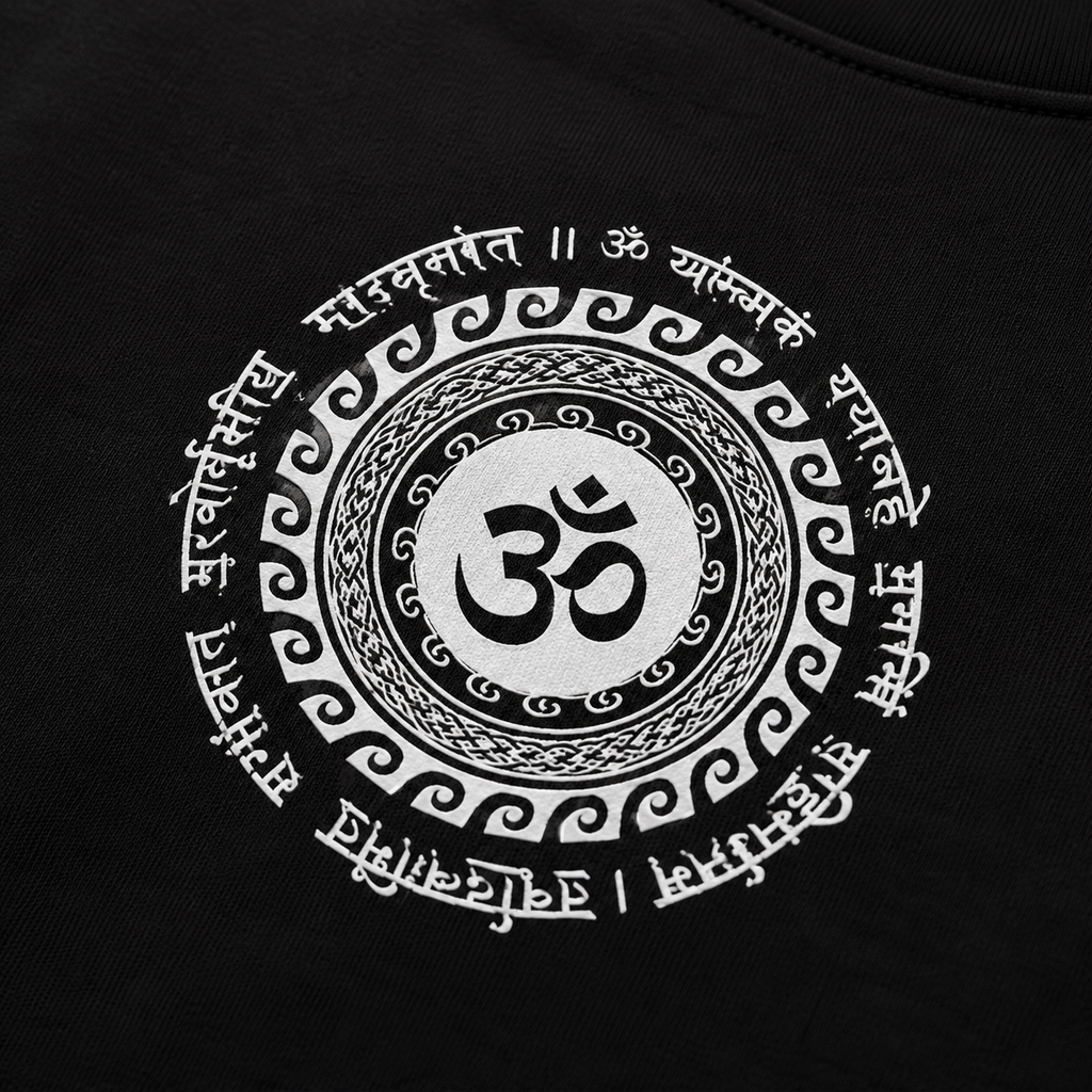 Close-up of a black garment featuring a large white circular graphic with an Om symbol in the center and decorative script around it.