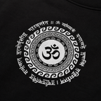 Close-up of a black garment featuring a large white circular graphic with an Om symbol in the center and decorative script around it.