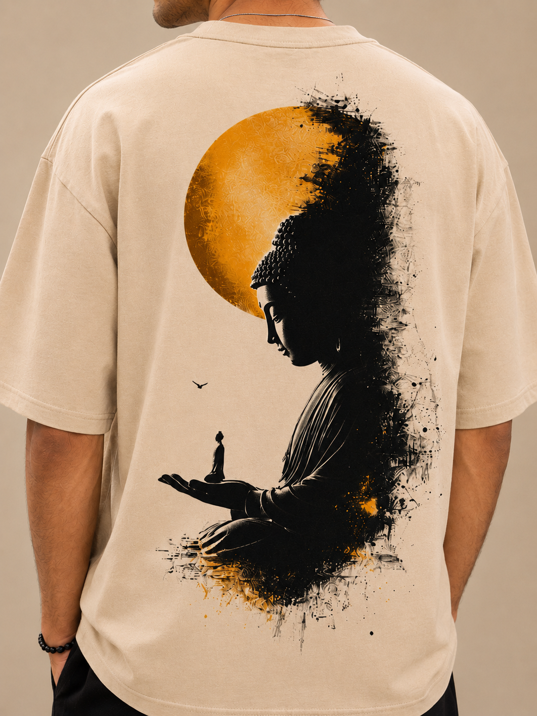 Close-up back view of beige T-shirt featuring detailed Buddha meditation artwork with golden sun