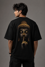 A man shown from the back wearing a black oversized T-shirt with a large graphic print of Buddha's face in gold and dark tones, posed against a solid gray studio background.