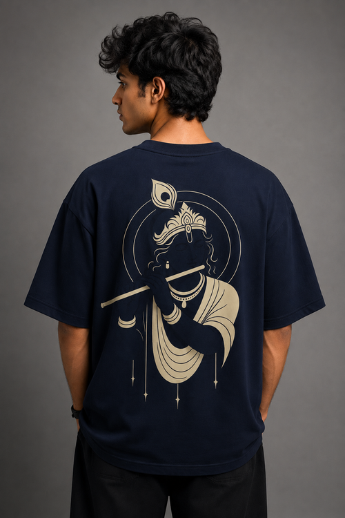 A man shown from the back wearing a navy blue t-shirt with a large cream-colored graphic of Lord Krishna on the back, set against a solid gray studio background.